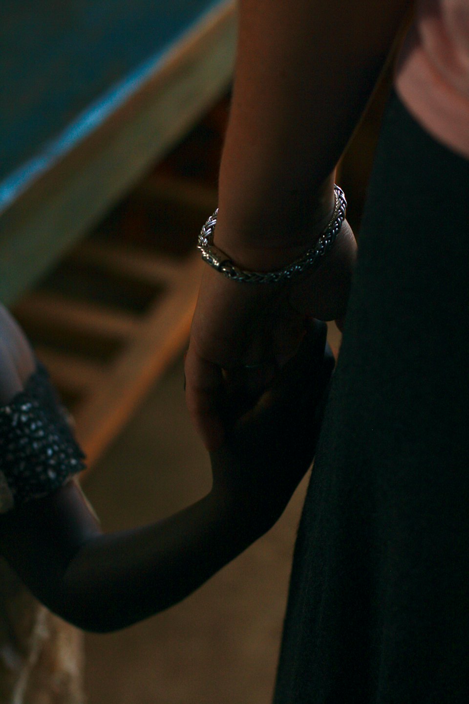 Two people holding hands, one wearing a bracelet.